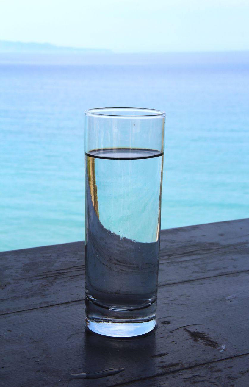 glass of water by the turquoise sea