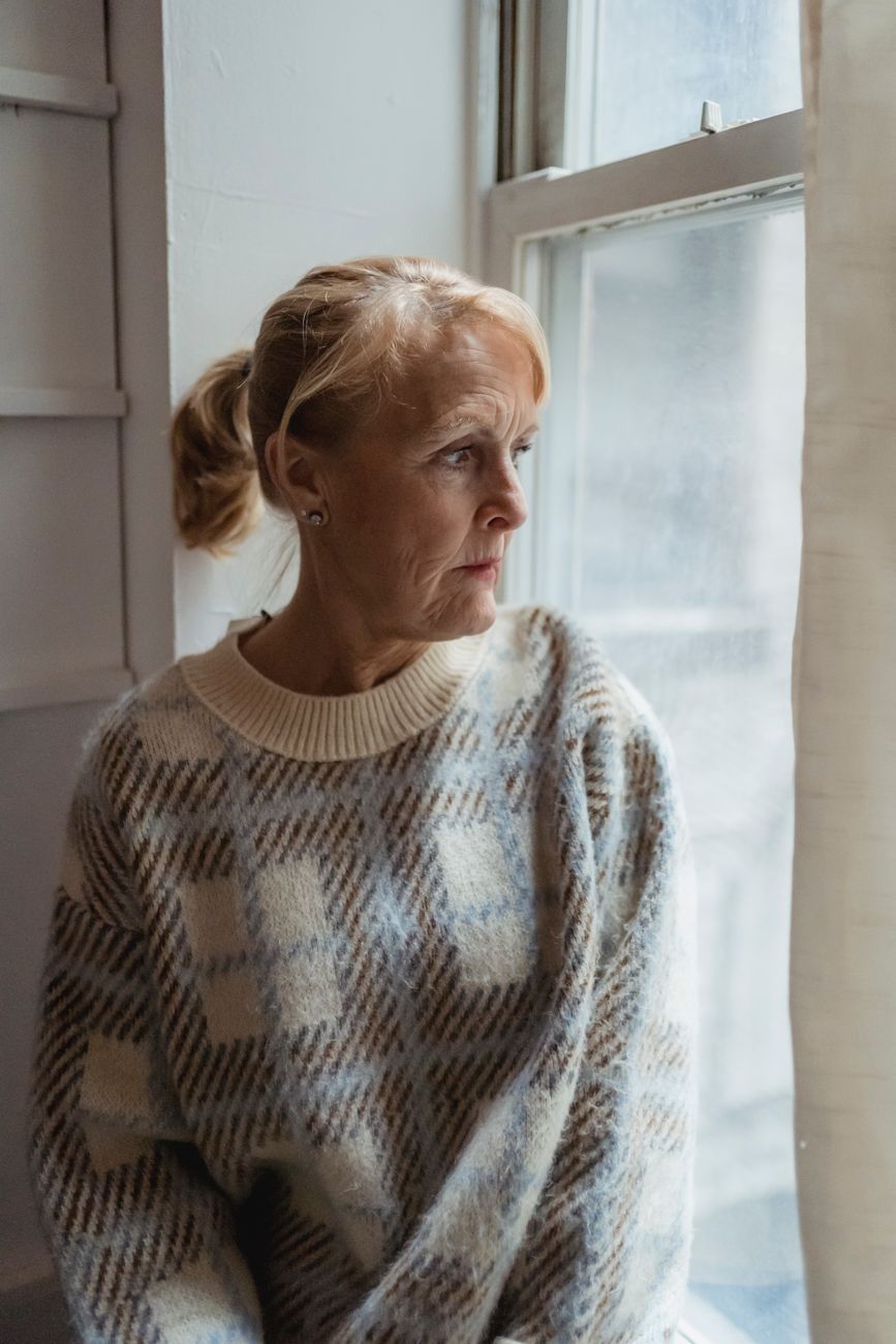 serious senior woman sitting near window